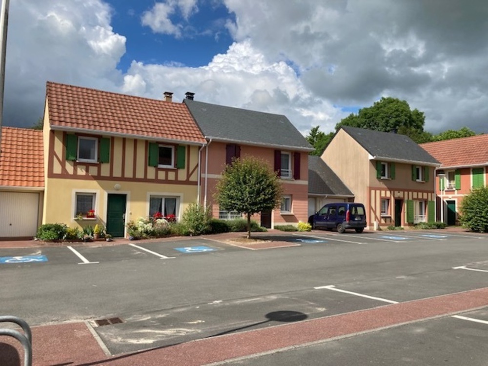Maison rose avec petit jardin à l'arrière, parking devant